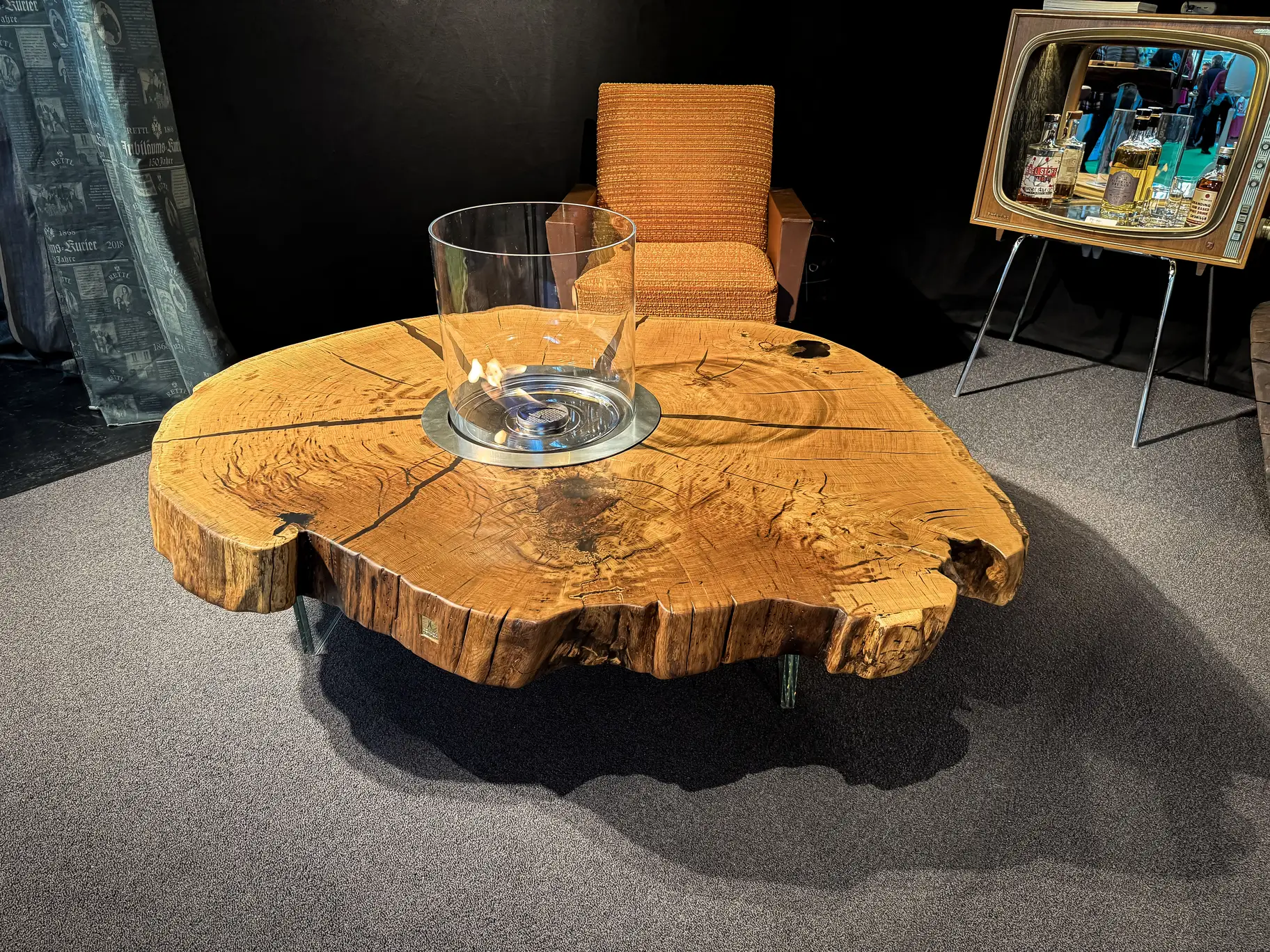 Eichen-Couchtisch mit Naturkante und Feuerbereich aus einer Baumstammscheibe, arrangiert neben einem modernen Couchsessel