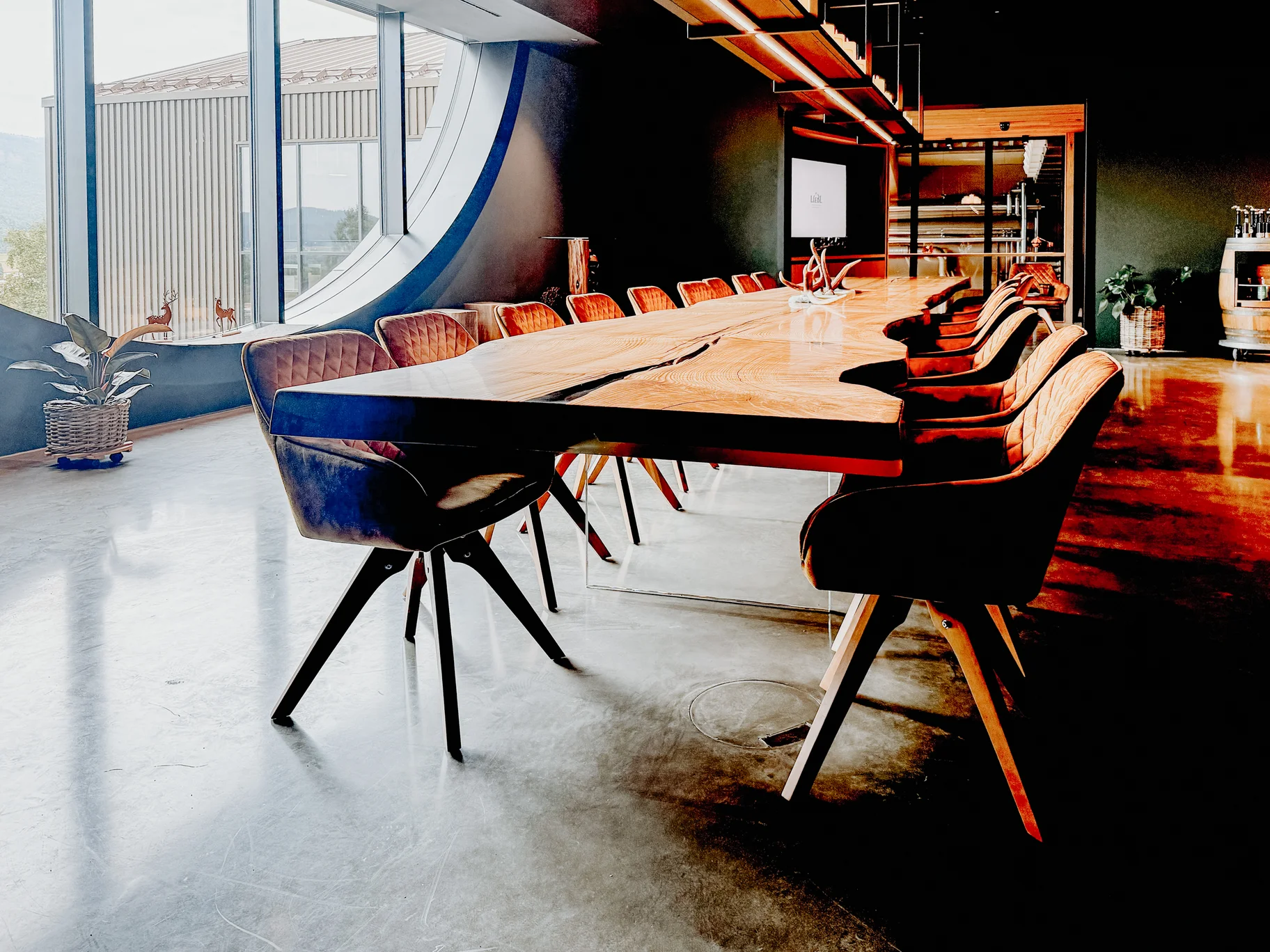 Table en bois massif de Stammdesign issue d’un seul tronc de frêne, avec bord naturel, pieds en verre et forte présence dans un loft
