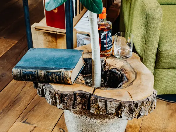 Maceta creativa de Stammdesign como mesa auxiliar con un libro antiguo y una botella de whisky