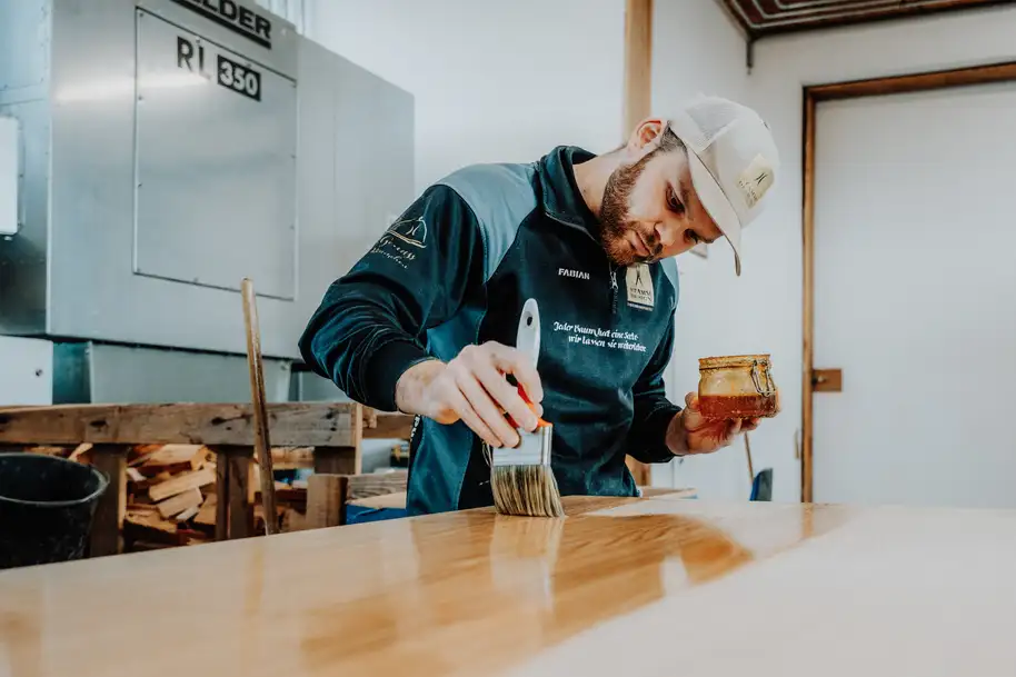 Hombre trabajando en una mesa con un pincel y aceite para una superficie protegida