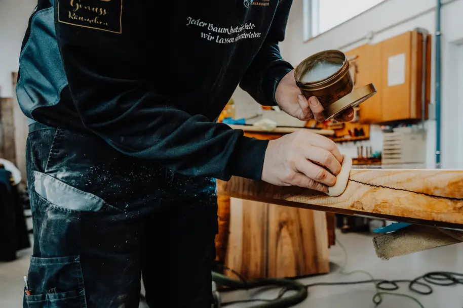 Esperto di legno tratta un piano di tavolo con cera per una superficie rifinita