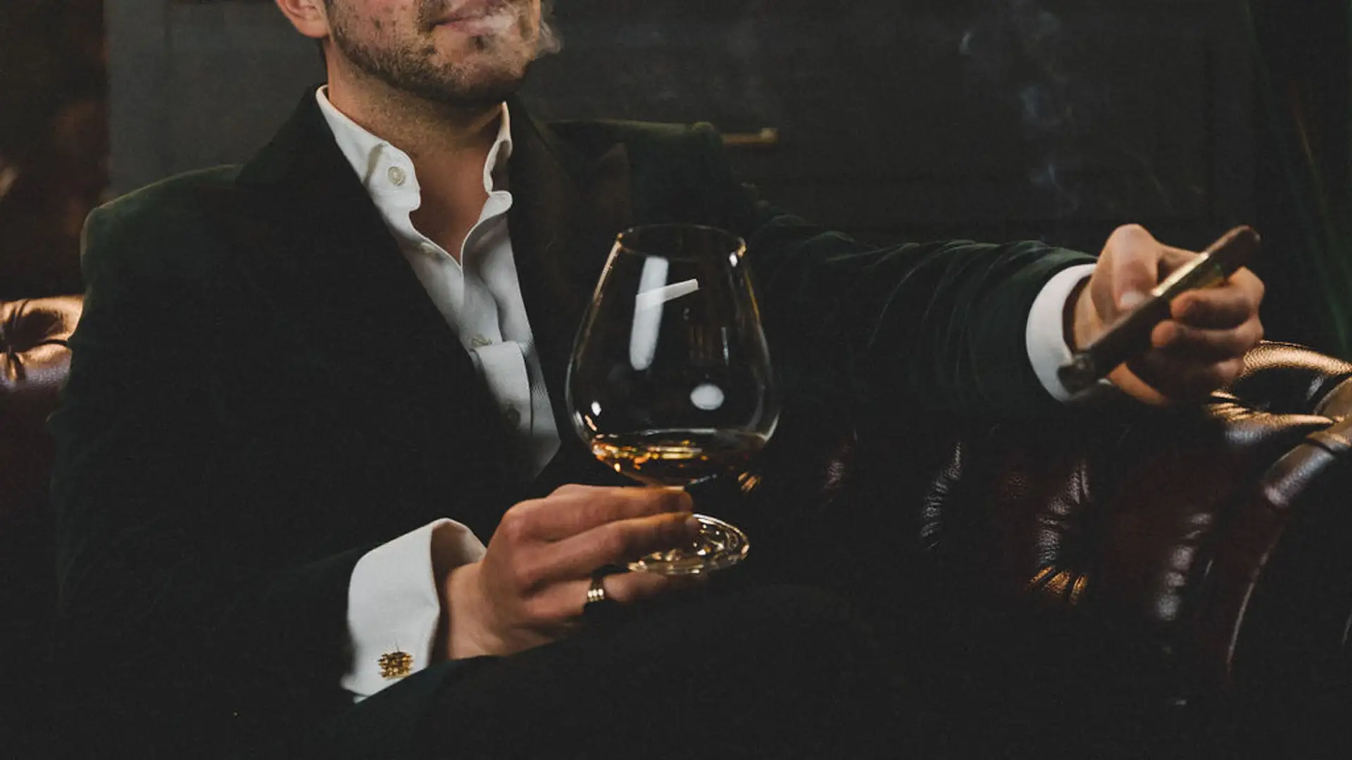 L'uomo fuma con piacere un sigaro e tiene un bicchiere di rum
