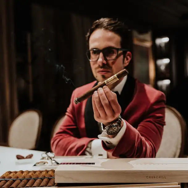 Uomo in abito rosso presenta un sigaro