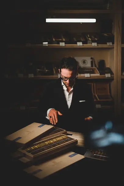 Man selects a cigar from a large, premium cigar selection