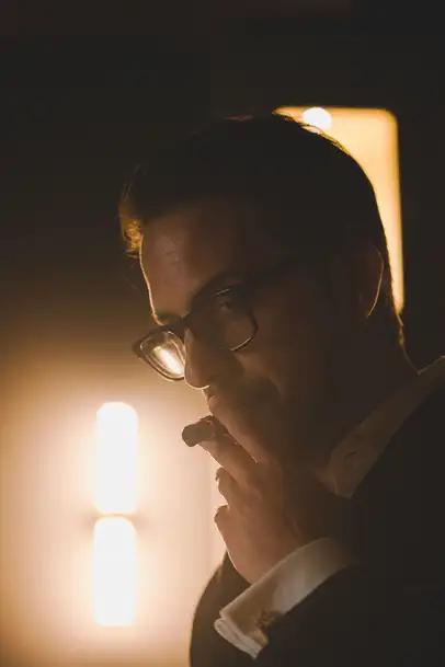 Uomo in abito elegante assapora un tiro da un sigaro