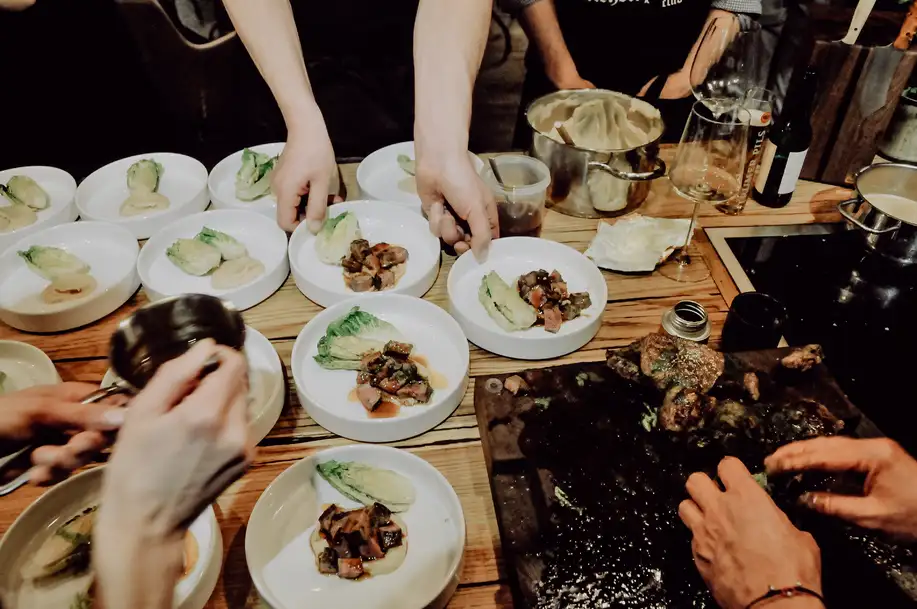 Mehrere Teller mit Gourmet-Essen, Hände richten das Essen kunstvoll an