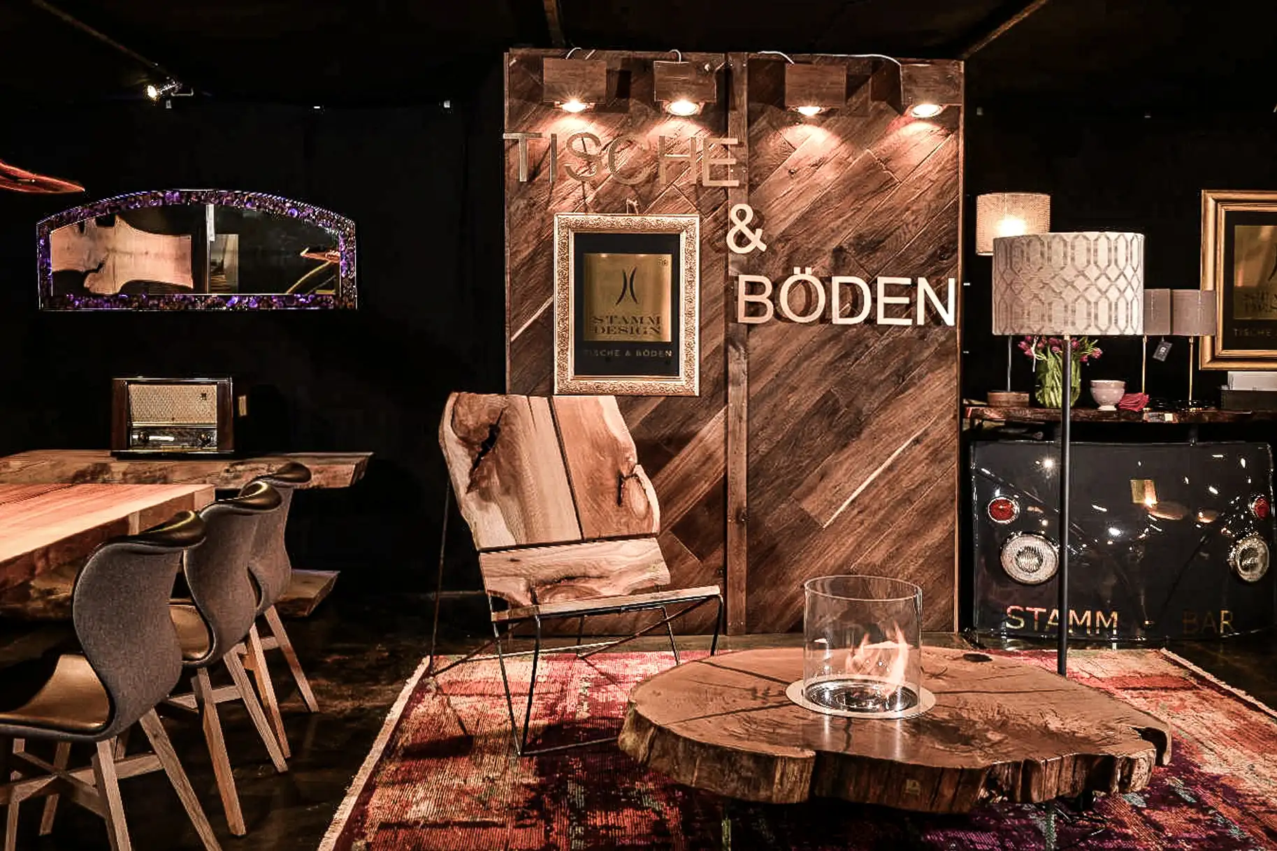 Stand espositivo di Stammdesign con poltrona in legno massello, tavolino in tronco d'albero e camino