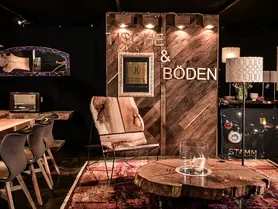 Stand de exposición de Stammdesign con sillón de madera maciza, mesa de café de tronco de árbol y chimenea