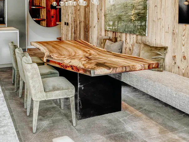 Mesa de comedor natural hecha de un tronco de árbol con vetas de madera distintivas y patas de vidrio de nogal.