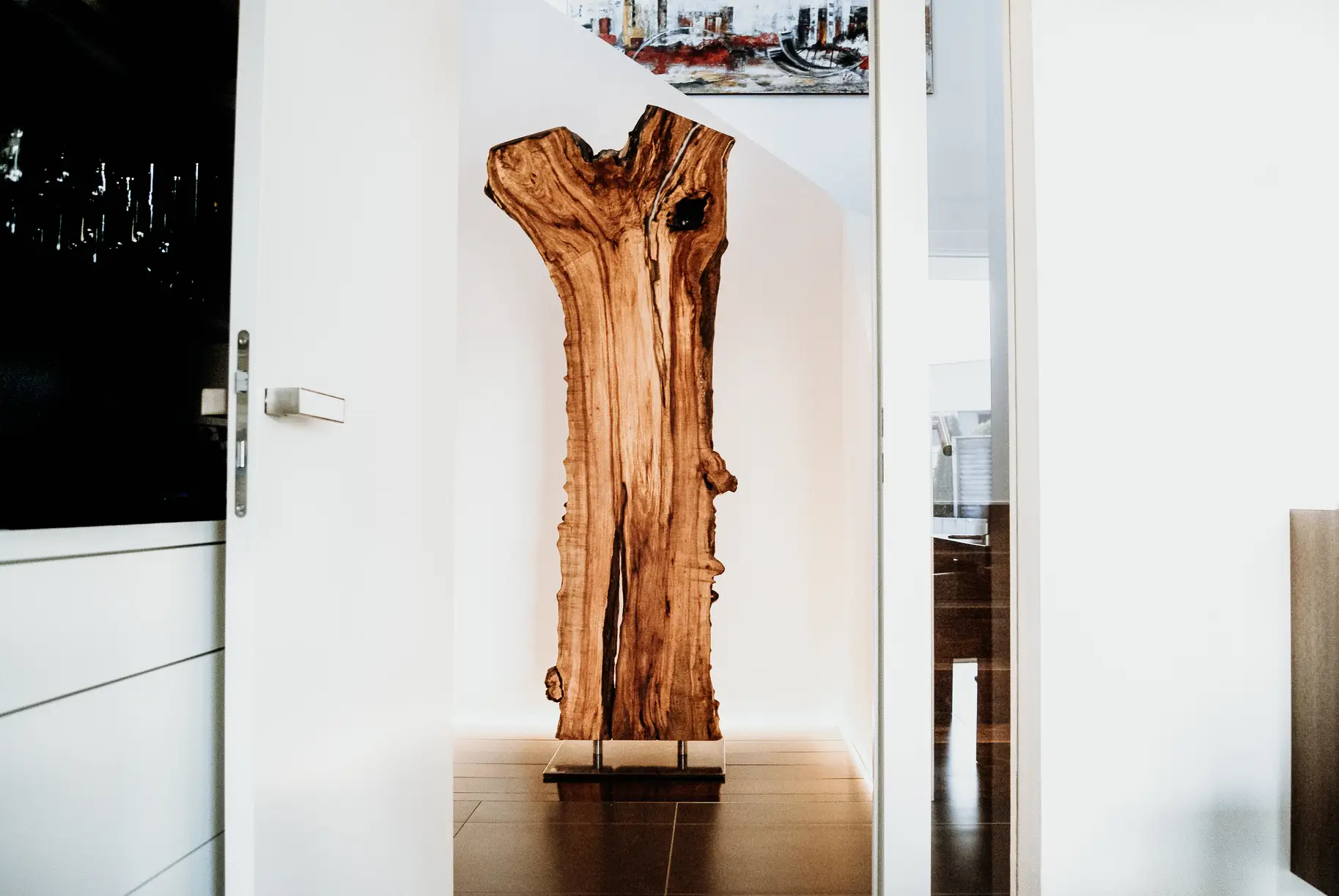 Escultura de madera de Stammdesign hecha de un tronco de árbol, de pie con soporte metálico para interiores modernos.