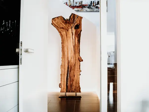 Escultura de madera de Stammdesign hecha de un tronco de árbol, de pie con soporte metálico para interiores modernos.