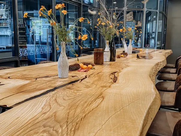 Mesa alta de alta calidad hecha de un tronco de árbol con borde natural de madera de fresno, vista en detalle.