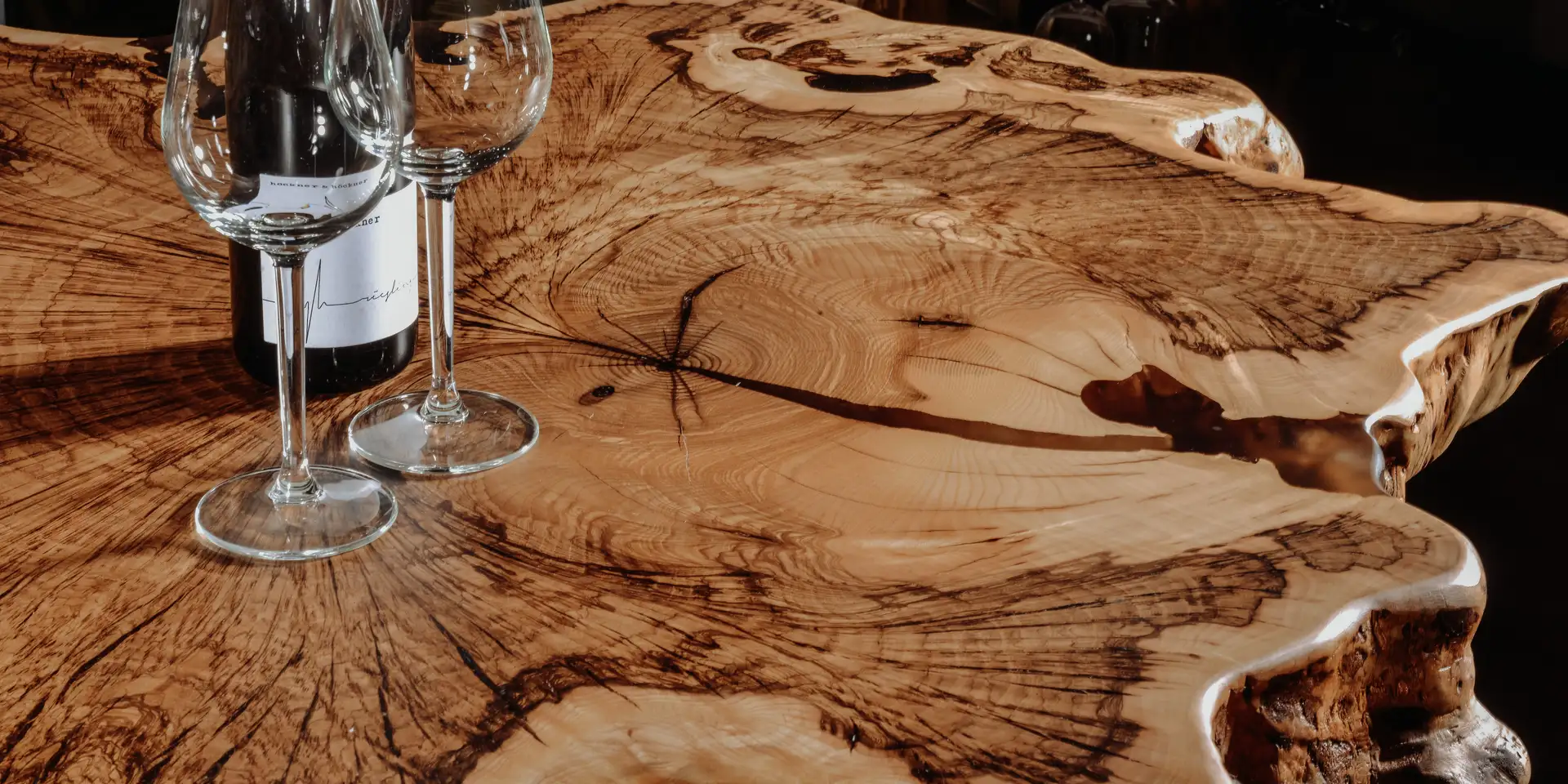 Mesa alta de diseño hecha de una rodaja de árbol de madera maciza con base de vidrio estable para gastronomía y bares, detalles.