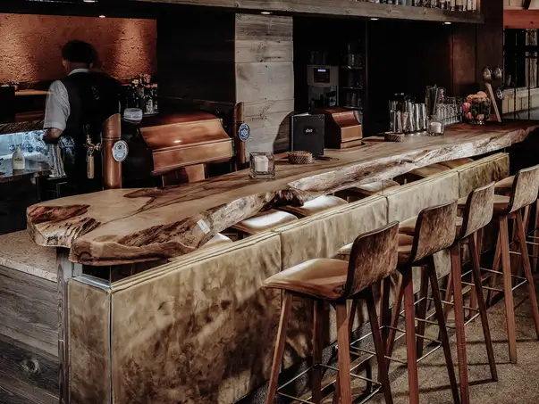 Top bar artigianali in legno di tronco d'albero con superficie elegante, ideali per la ristorazione di Stammdesign.