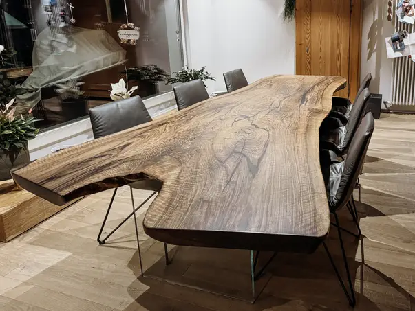 Mesa de madera maciza hecha de un tronco con una estructura de madera distintiva y patas de vidrio de nogal.