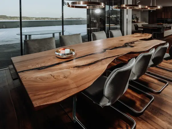 Mesa de comedor rústica hecha de tronco de olmo con patas de vidrio y borde natural, vista lateral