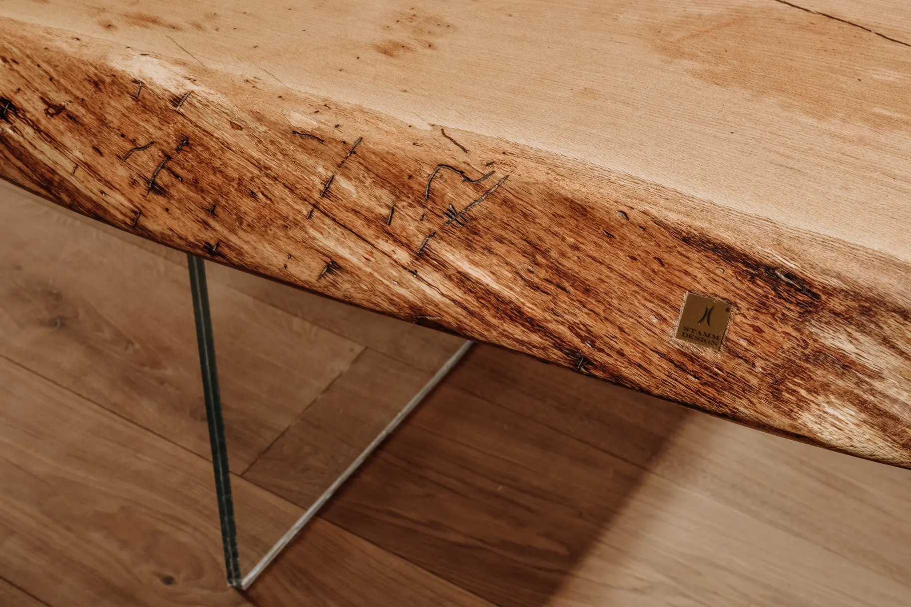 Naturbelassener Esszimmertisch aus einem Baumstamm mit markanter Holzstruktur und Glasbeinen, Detailansicht