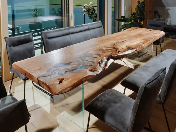 Mesa de comedor de madera maciza con bordes naturales y patas de vidrio