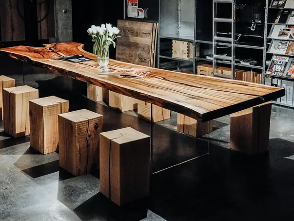 Gran mesa de comedor hecha de un tronco con base de madera estable y superficie de madera natural elegante, vista lateral