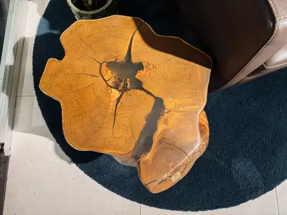 Modern dark robinia side table with natural live edge and glass base for living spaces