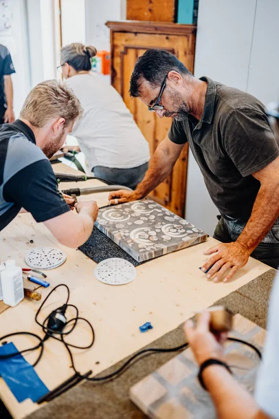 Stammdesign-Mitarbeiter erklärt einem Kursteilnehmer den nächsten Arbeitsschritt